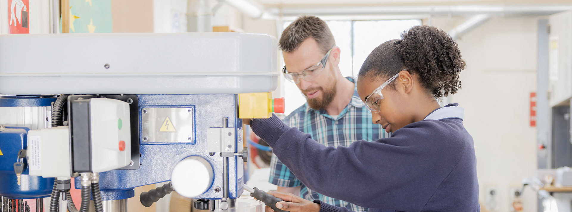 A teacher and his student using machinery in the workshop at St Columba’s Catholic College Springwood