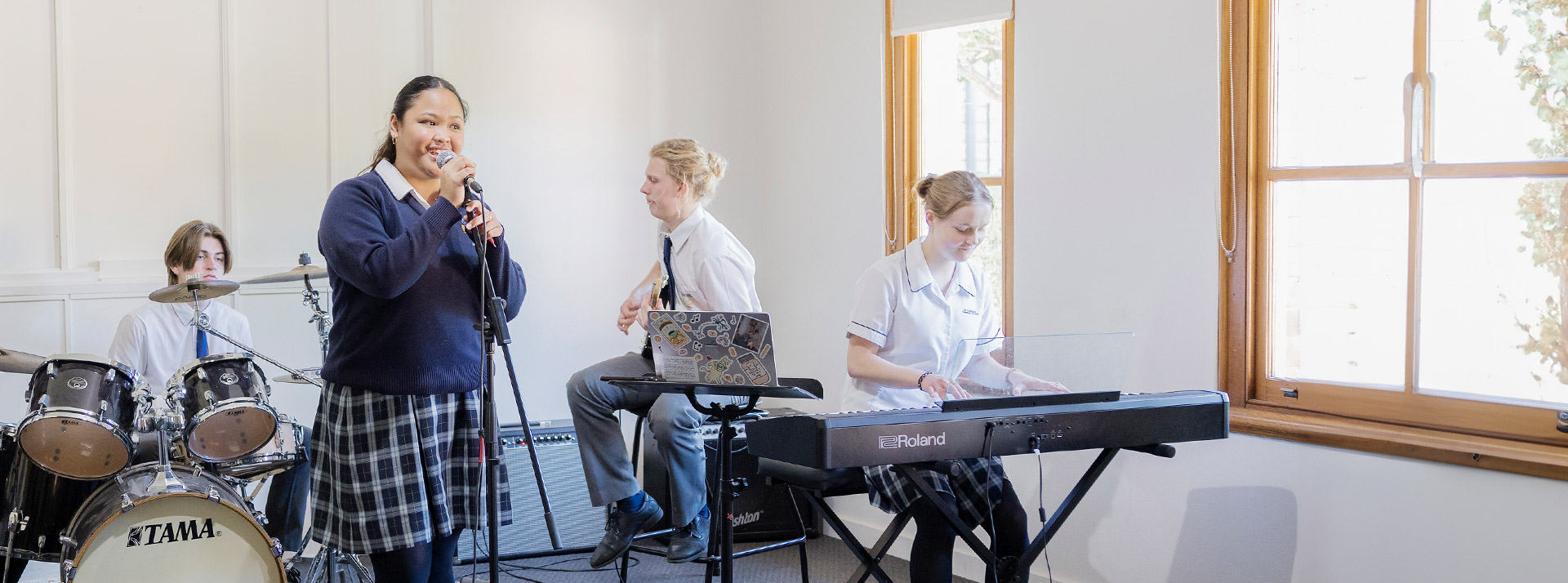 Students singing, playing drums, keyboard and guitar in music class at St Columba’s Catholic College Springwood