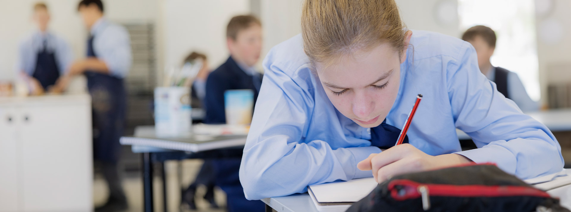 Student writing in her workbook in the classroom at St Columba’s Catholic College Springwood