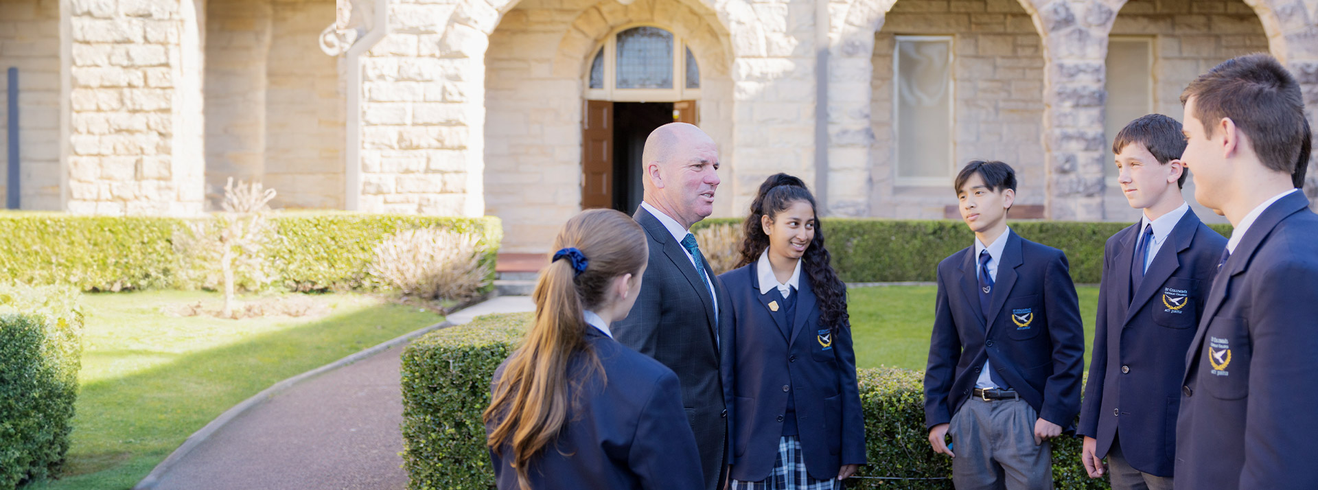 Principal Phillip Scollard with students in the school grounds at St Columba’s Catholic College Springwood