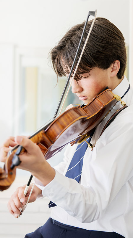 Student practising violin in music class at St Columba’s Catholic College Springwood