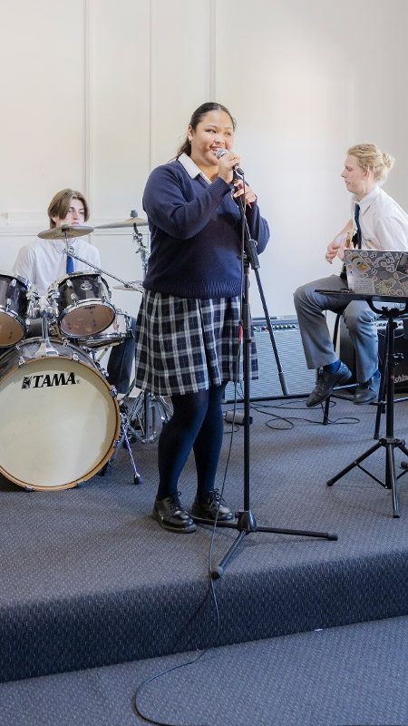 Students singing, playing drums, keyboard and guitar in music class at St Columba’s Catholic College Springwood