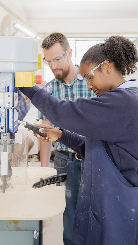 Teacher supervising his student on a woodworking machinery in class at St Columba’s Catholic College Springwood