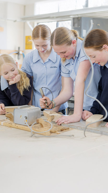 Students in the woodwork room engraving timber at St Columba’s Catholic College Springwood