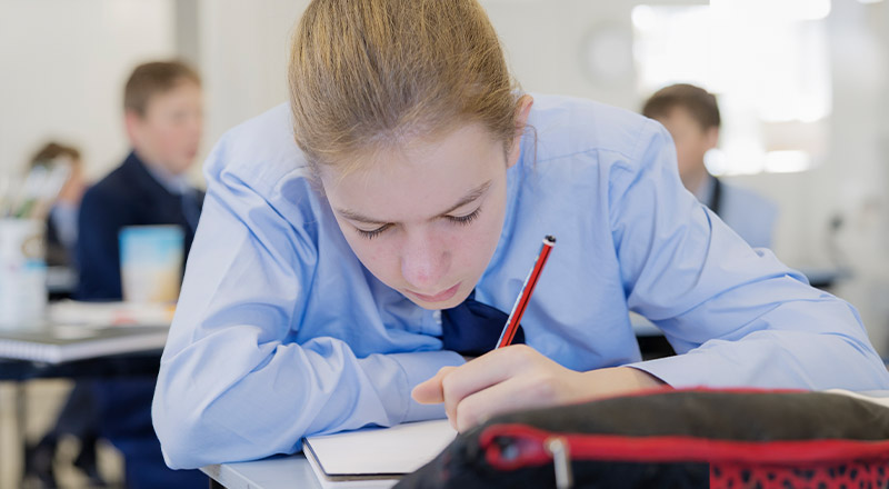 Student writing in her workbook in the classroom at St Columba’s Catholic College Springwood