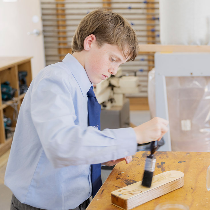 Student varnishing his wood work project at St Columba’s Catholic College Springwood